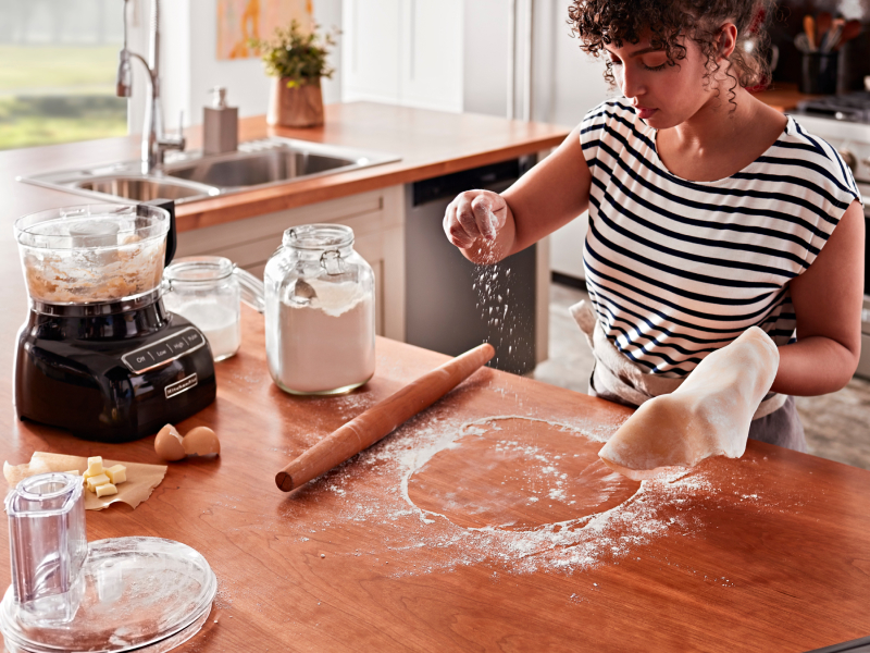 Person dusting flour on a rolling surface