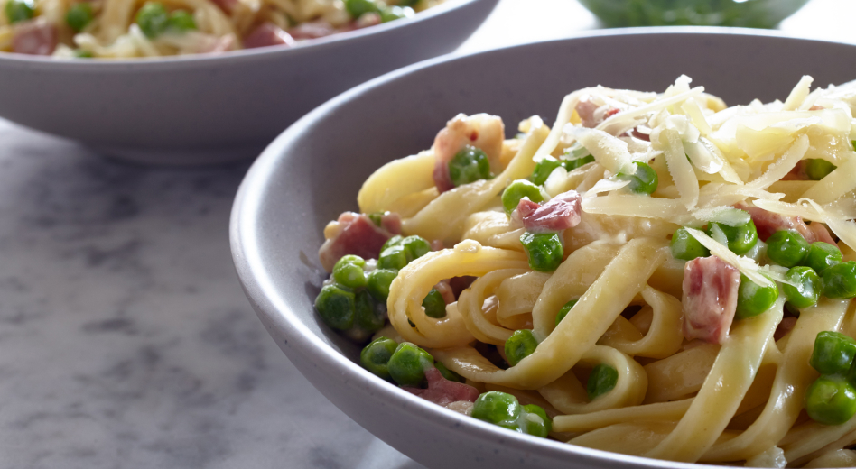 Fettuccine with cream sauce topped with peas, bacon and grated cheese Fettuccine with cream sauce topped with peas, bacon and grated cheese