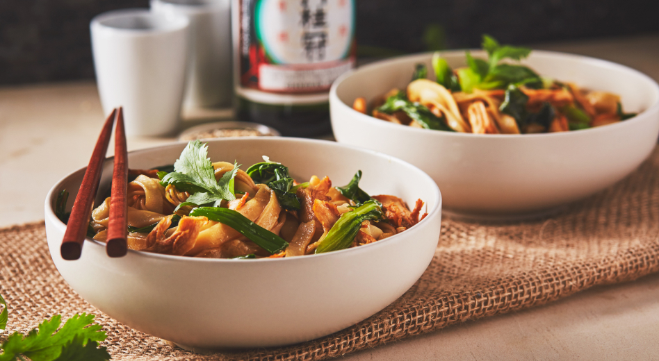 Two bowls of fettuccine noodles on a table with wooden chopsticks Two bowls of fettuccine noodles on a table with wooden chopsticks