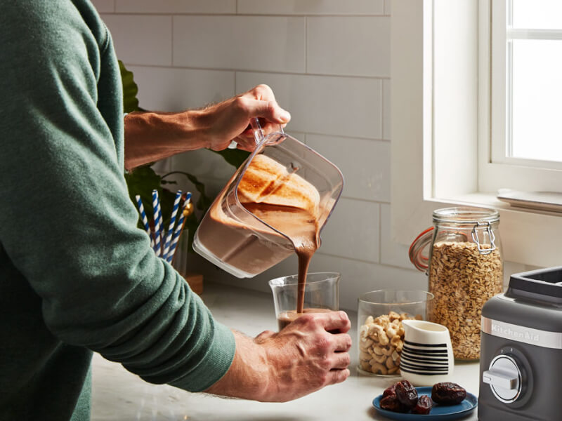 Person pouring a blended drink into a glass