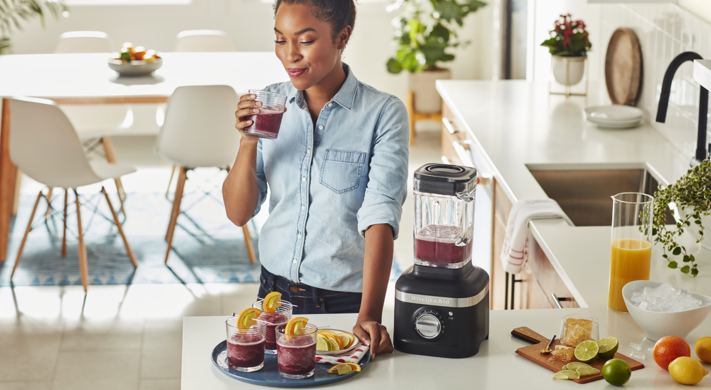 Person with a tray of cocktails, sipping from a glass Person with a tray of cocktails, sipping from a glass