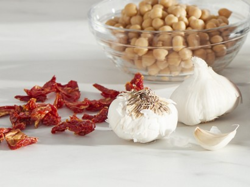 Chickpeas in bowl next to whole garlic and dried herbs