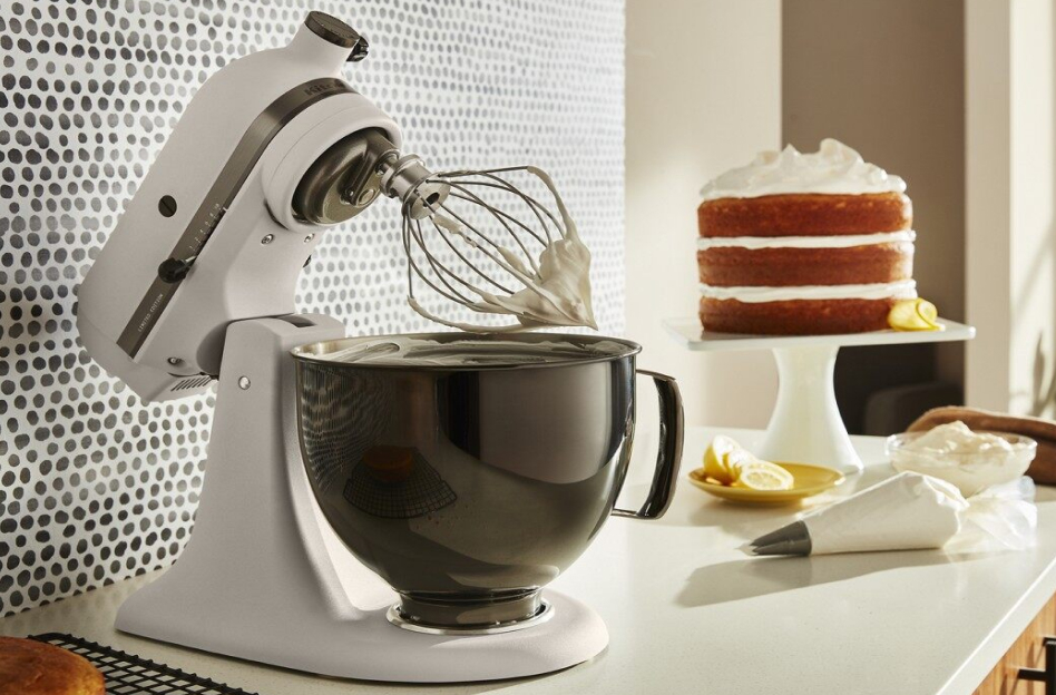 A KitchenAid® stand mixer with whisk attachment and a vanilla frosted cake  A KitchenAid® stand mixer with whisk attachment and a vanilla frosted cake