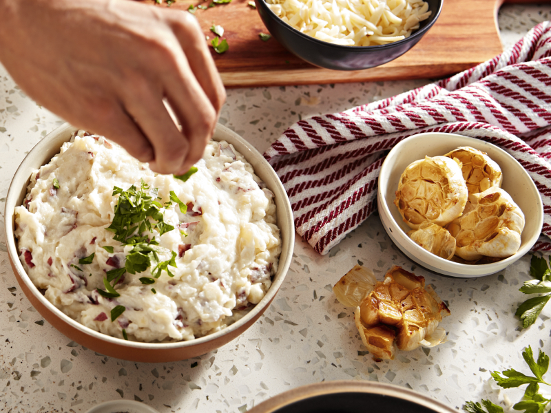 Roasted garlic beside a bowl of mashed red potatoes Roasted garlic beside a bowl of mashed red potatoes