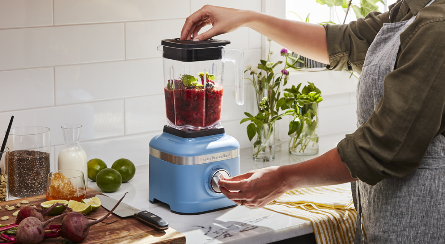 Woman with a KitchenAid® blender blending mixture in a modern kitchen