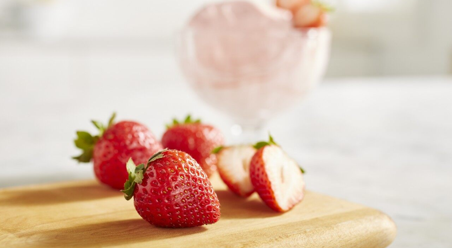 A closeup of fresh strawberries next to a dish of strawberry nice cream A closeup of fresh strawberries next to a dish of strawberry nice cream