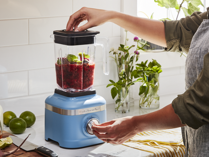 Woman with a KitchenAid® blender blending mixture in a modern kitchen Woman with a KitchenAid® blender blending mixture in a modern kitchen