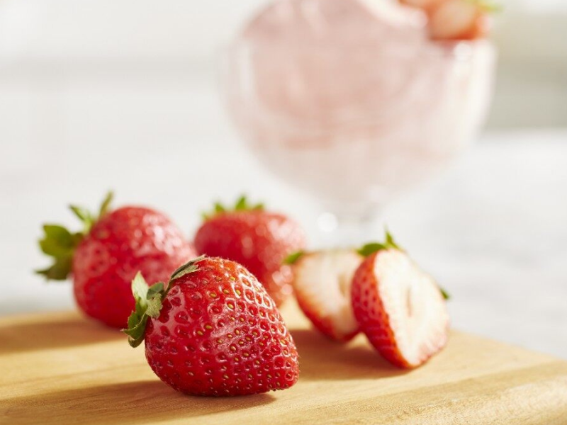 A closeup of fresh strawberries next to a dish of strawberry nice cream A closeup of fresh strawberries next to a dish of strawberry nice cream