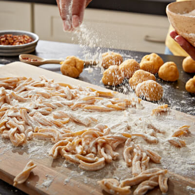 Hand sprinkling flour on fresh pasta