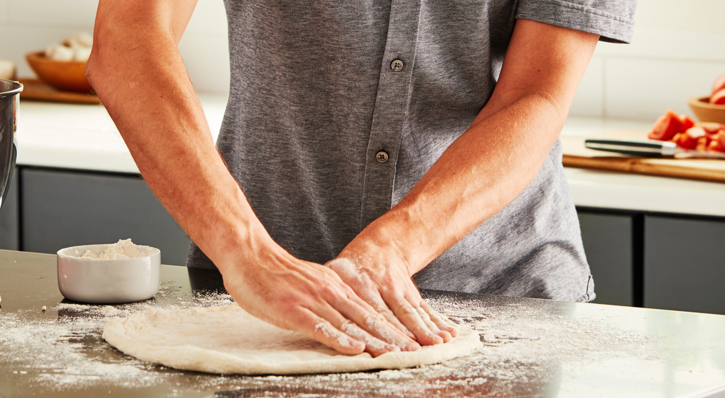 Person stretching out homemade pizza dough Person stretching out homemade pizza dough