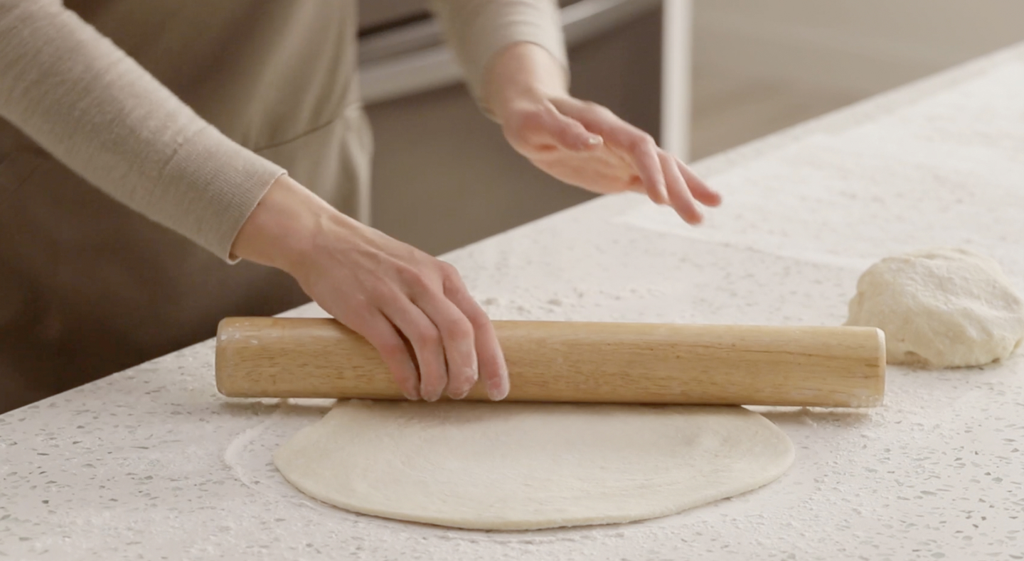 Person rolling out dough with a rolling pin Person rolling out dough with a rolling pin