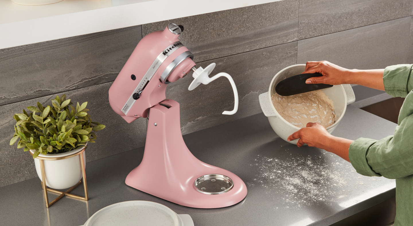 Woman removing dough from mixing bowl