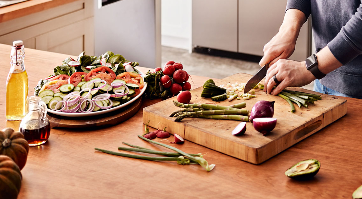 Maker chopping vegetables on wooden cutting board Maker chopping vegetables on wooden cutting board