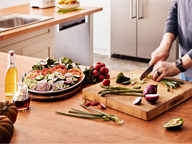 Maker chopping vegetables on wooden cutting board Maker chopping vegetables on wooden cutting board