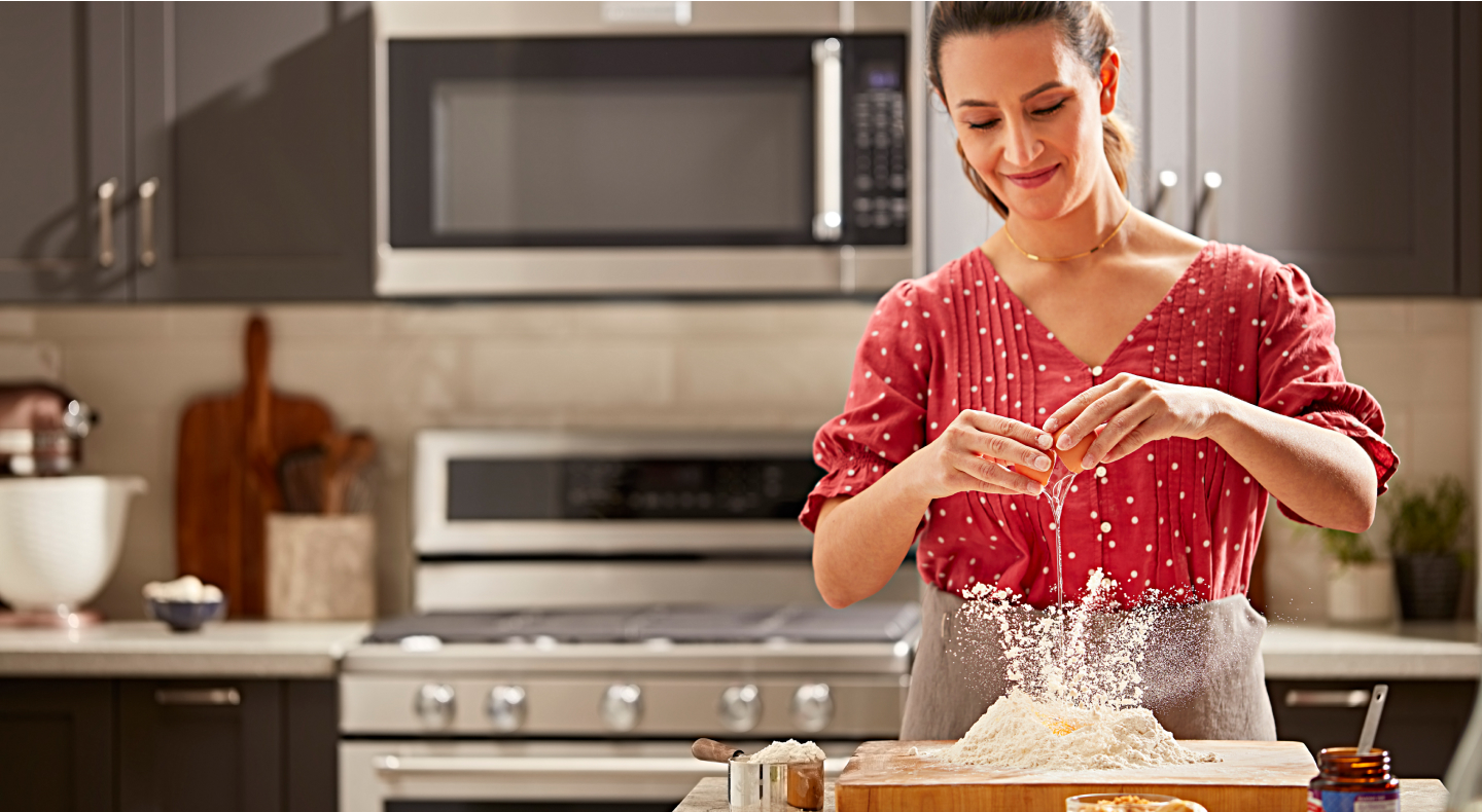 Woman adding eggs to flour mound Woman adding eggs to flour mound