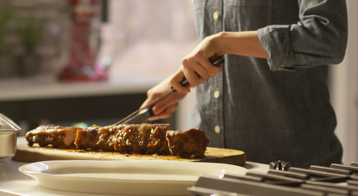 Cook cutting into a tender rack of ribs. Cook cutting into a tender rack of ribs.