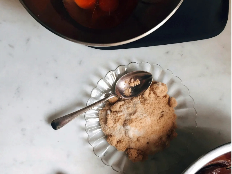Dish of dry ingredients next to a bowl of cracked eggs
