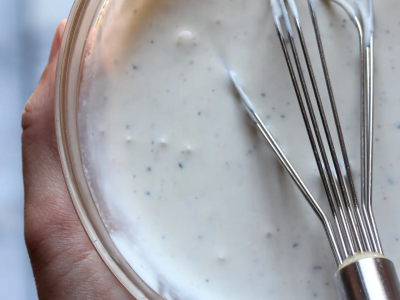 A whisk in a small bowl of tabouli dressing