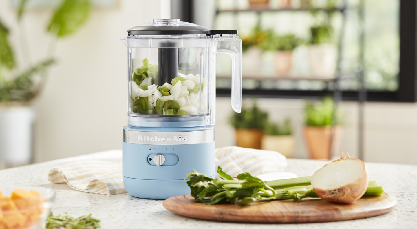 A KitchenAid® food processor filled with celery and onions A KitchenAid® food processor filled with celery and onions