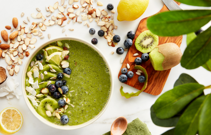 Overhead shot of the perfect green smoothie bowl surrounded by blueberries, seeds, sliced kiwi, lemon and almonds Overhead shot of the perfect green smoothie bowl surrounded by blueberries, seeds, sliced kiwi, lemon and almonds