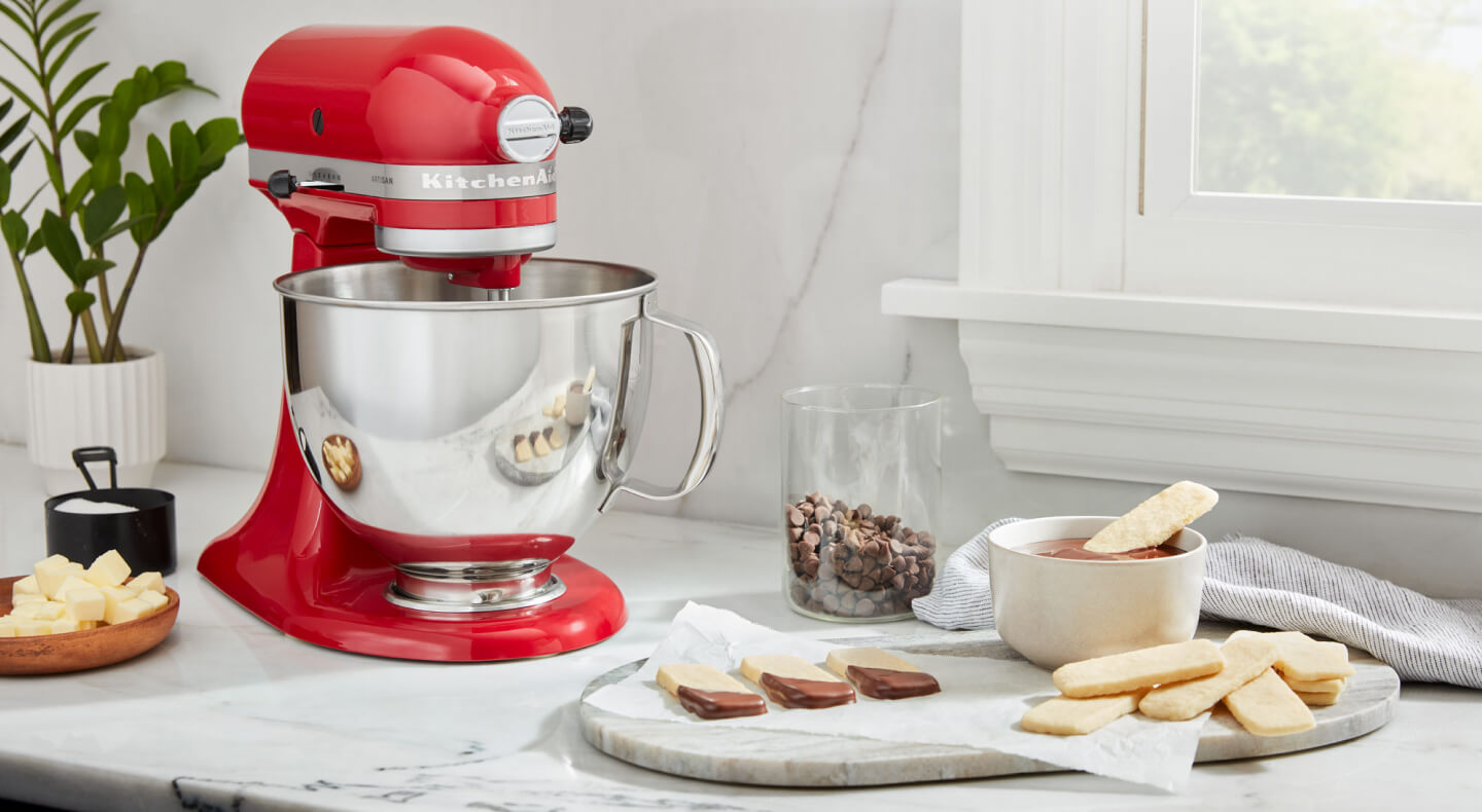 A red KitchenAid® stand mixer and a prepared dessert on a countertop  A red KitchenAid® stand mixer and a prepared dessert on a countertop