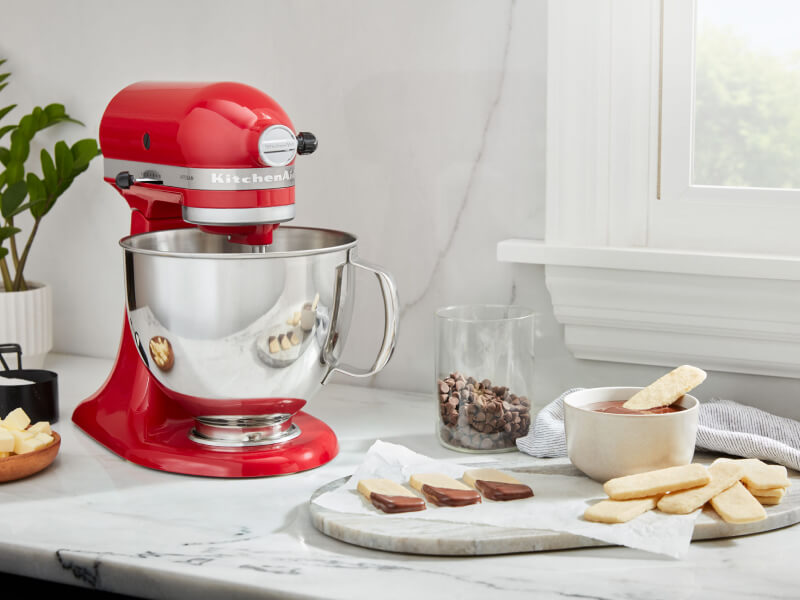 A red KitchenAid® stand mixer and a prepared dessert on a countertop  A red KitchenAid® stand mixer and a prepared dessert on a countertop
