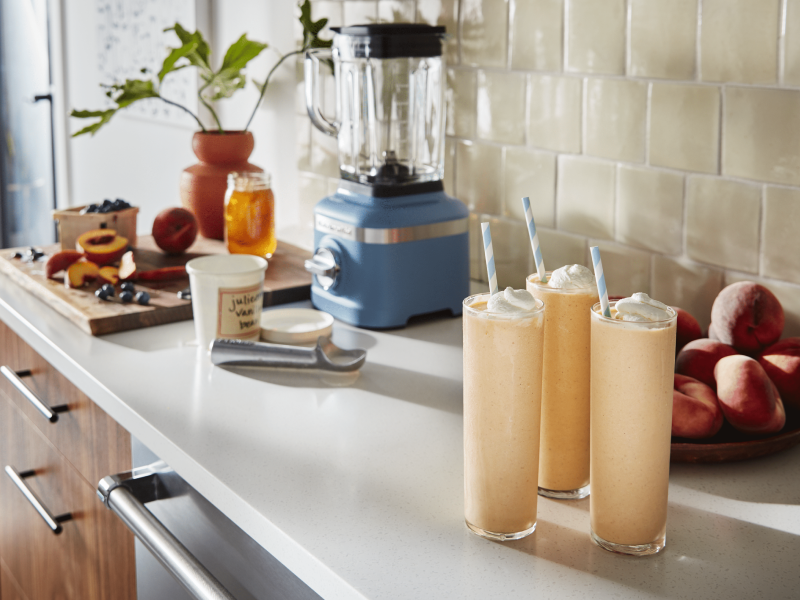 Three glasses of milkshakes topped with whipped cream on a countertop Three glasses of milkshakes topped with whipped cream on a countertop