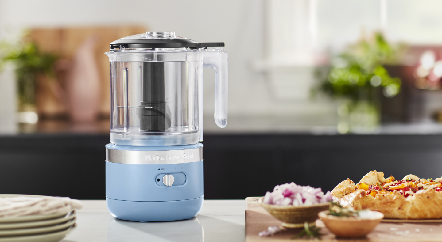 A KitchenAid® food processor with ingredients sitting next to it A KitchenAid® food processor with ingredients sitting next to it
