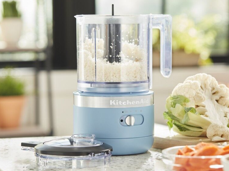 KitchenAid® food processor on a counter next to fresh vegetables in a modern kitchen.  KitchenAid® food processor on a counter next to fresh vegetables in a modern kitchen.