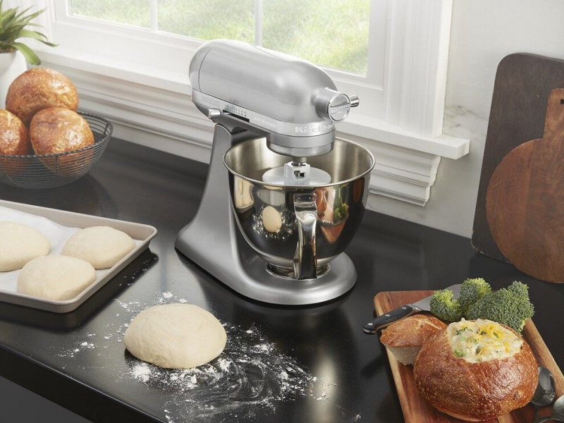 Shaped bread dough on countertop next to a silver KitchenAid® stand mixer