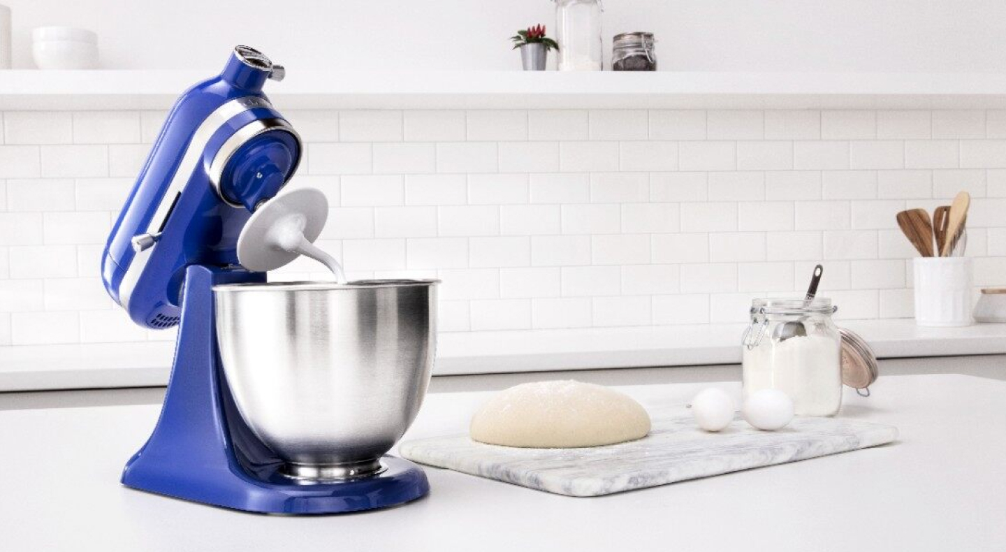 Blue KitchenAid® stand mixer next to a cutting board with bread dough and ingredients Blue KitchenAid® stand mixer next to a cutting board with bread dough and ingredients