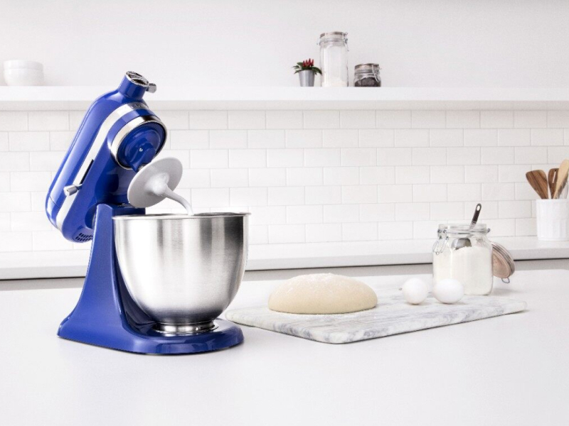 Blue KitchenAid® stand mixer next to a cutting board with bread dough and ingredients Blue KitchenAid® stand mixer next to a cutting board with bread dough and ingredients