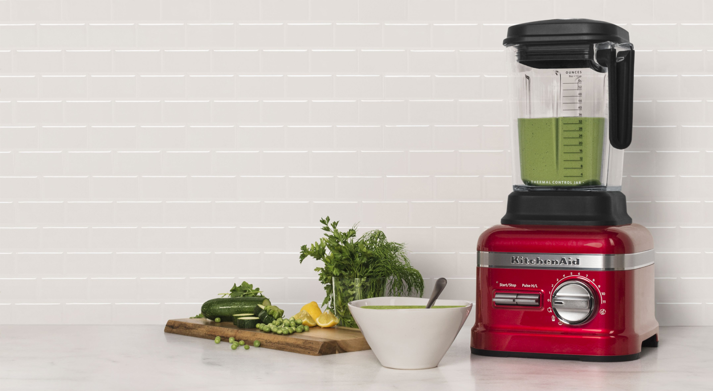 Red KitchenAid® blender next to various vegetables Red KitchenAid® blender next to various vegetables