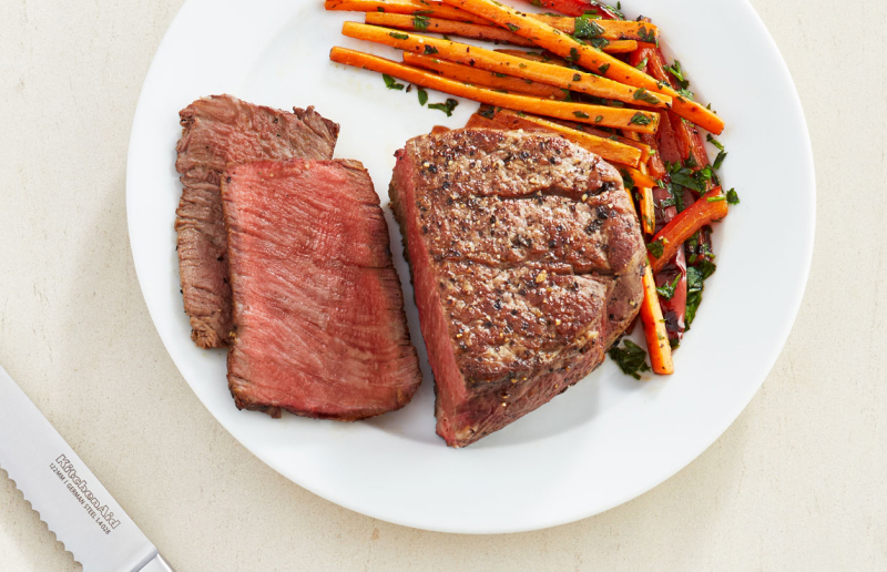 A half cut seasoned steak dish with carrots on the side A half cut seasoned steak dish with carrots on the side