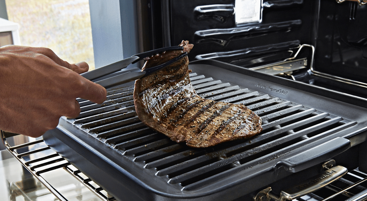 Hand lifting a cut of steak off of a rack Hand lifting a cut of steak off of a rack