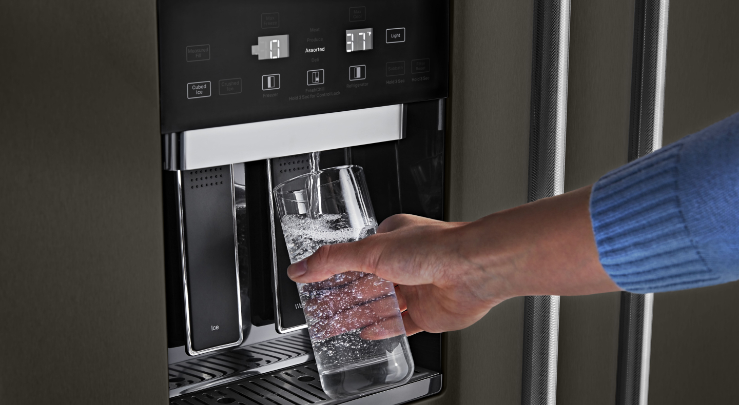 Person filling water from refrigerator dispenser Person filling water from refrigerator dispenser