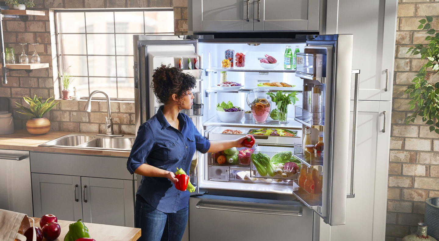 Person removing produce from KitchenAid® refrigerator Person removing produce from KitchenAid® refrigerator