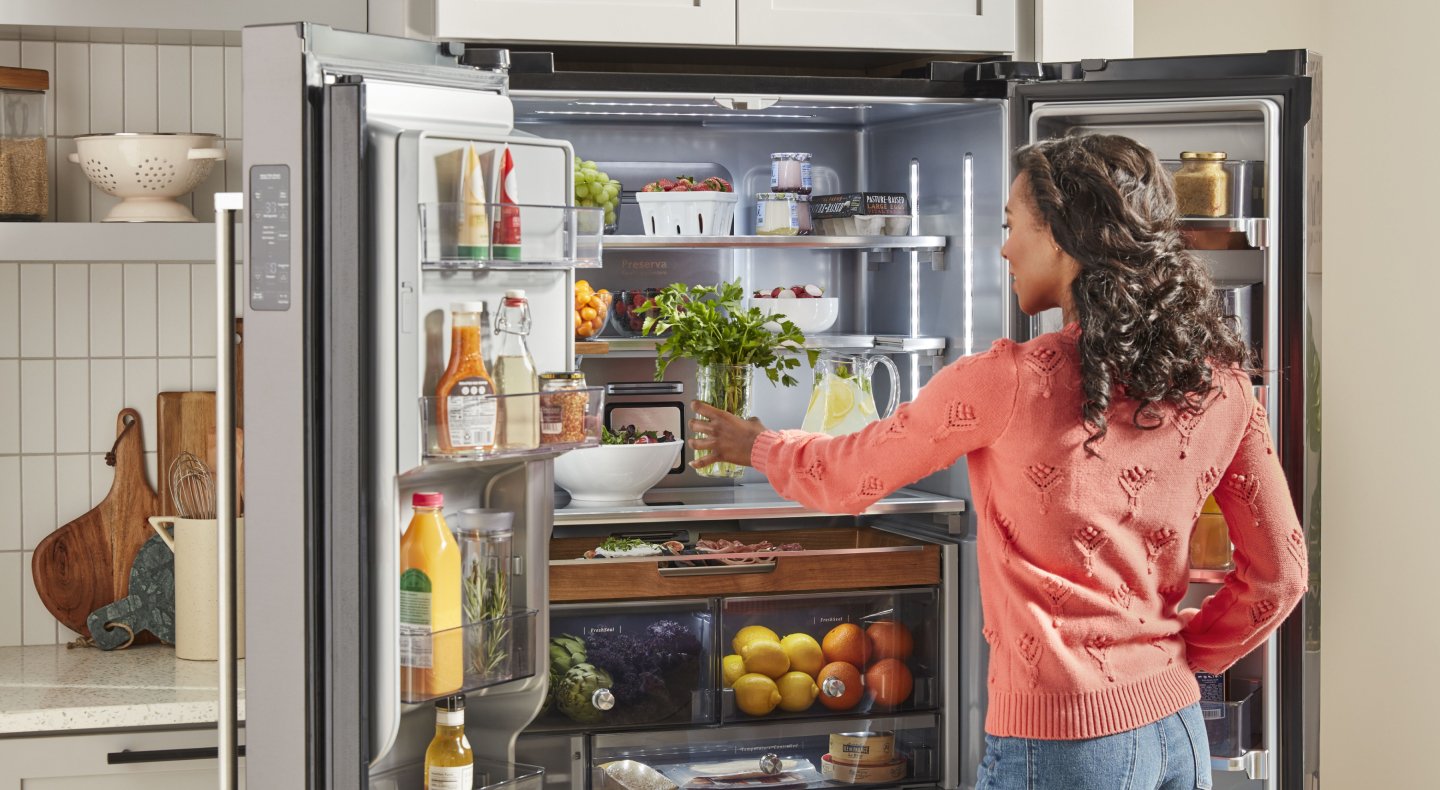 Person placing produce in a refrigerator Person placing produce in a refrigerator