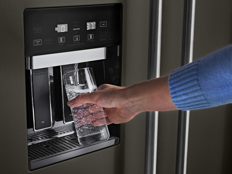 Person filling water from refrigerator dispenser Person filling water from refrigerator dispenser