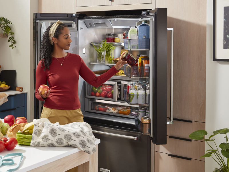 Person removing items from the door of a refrigerator Person removing items from the door of a refrigerator