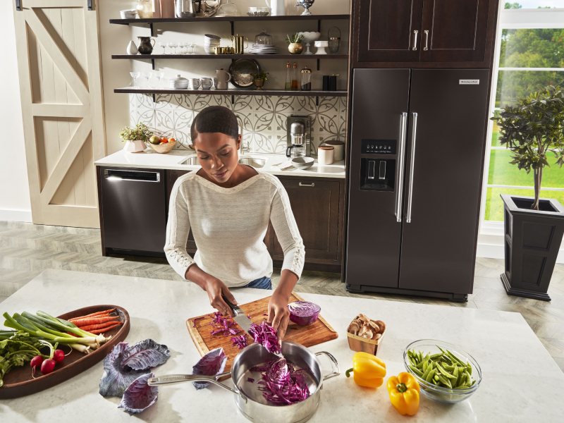 Person prepping ingredients in front of a refrigerator Person prepping ingredients in front of a refrigerator