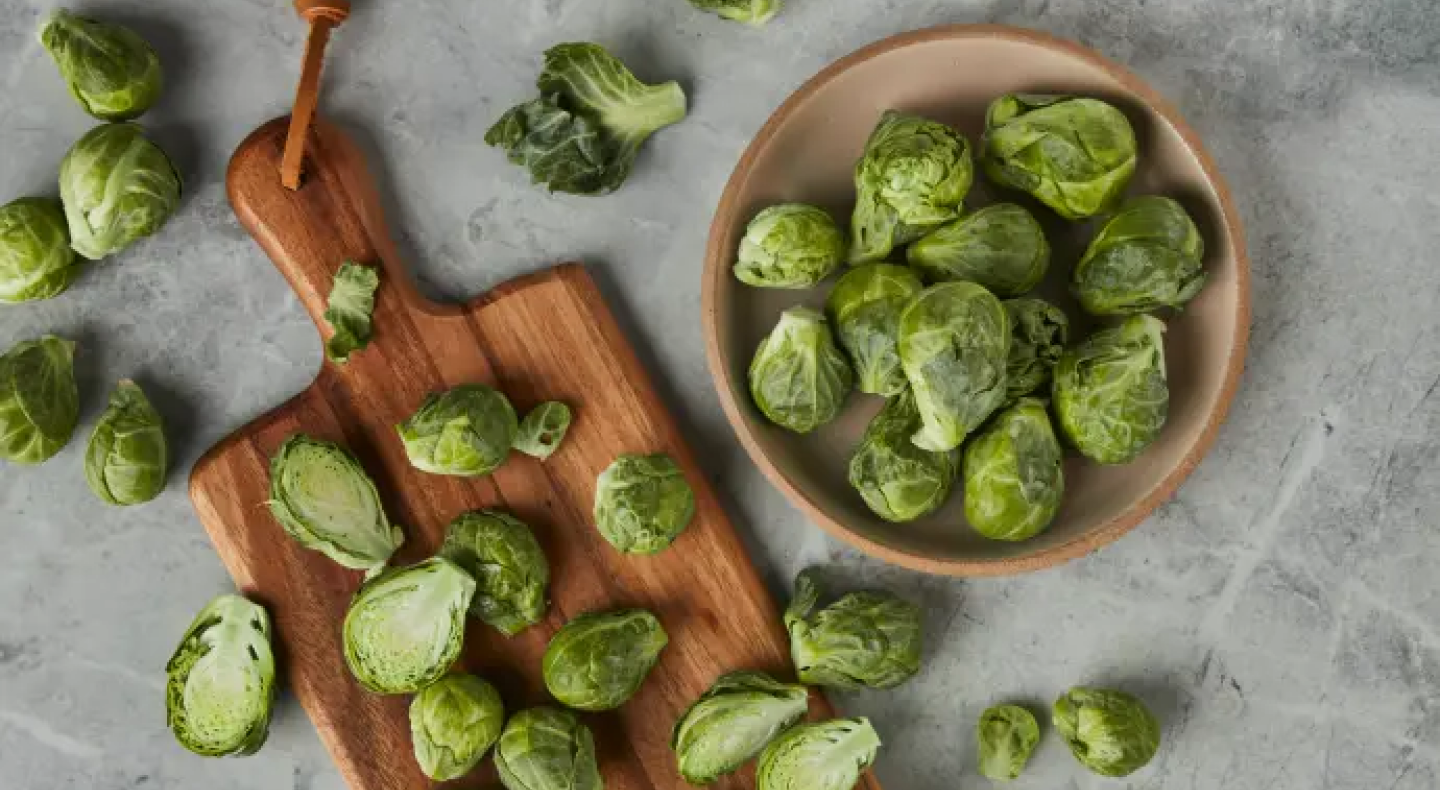 Bowl of Brussels sprouts next to sliced Brussels sprouts on a cutting board Bowl of Brussels sprouts next to sliced Brussels sprouts on a cutting board