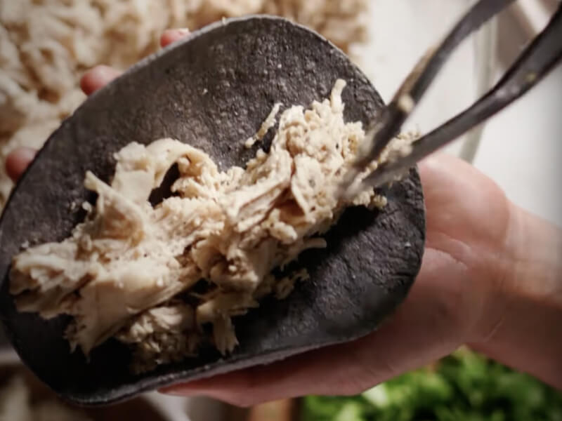 Shredded chicken on a tortilla.