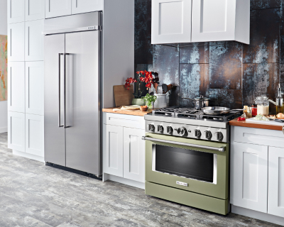 Kitchen with olive green stove, white cabinetry and french door refrigerator with ingredients on countertop