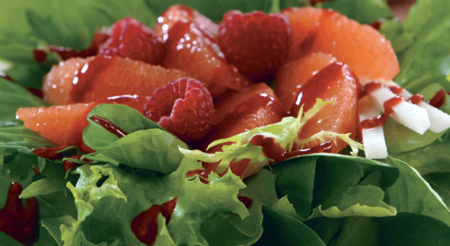 Close-up of raspberries and grapefruit topping shredded greens  Close-up of raspberries and grapefruit topping shredded greens