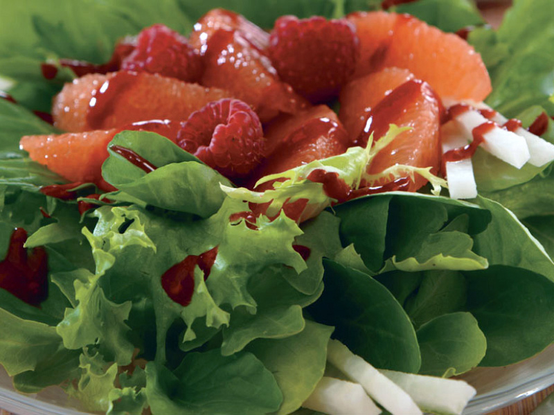 Close-up of raspberries and grapefruit topping shredded greens  Close-up of raspberries and grapefruit topping shredded greens
