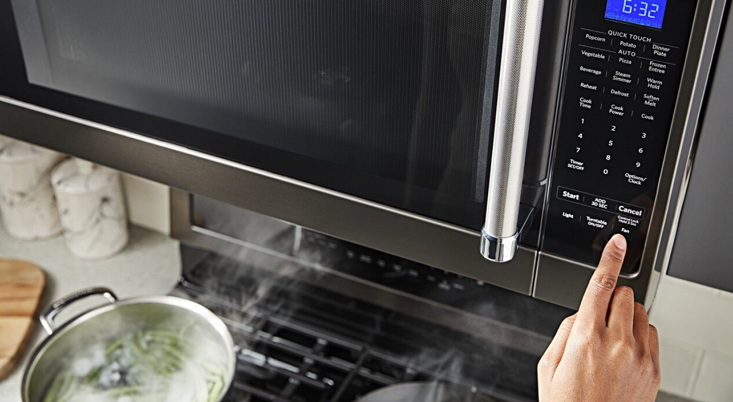 Person selecting a microwave preset button Person selecting a microwave preset button