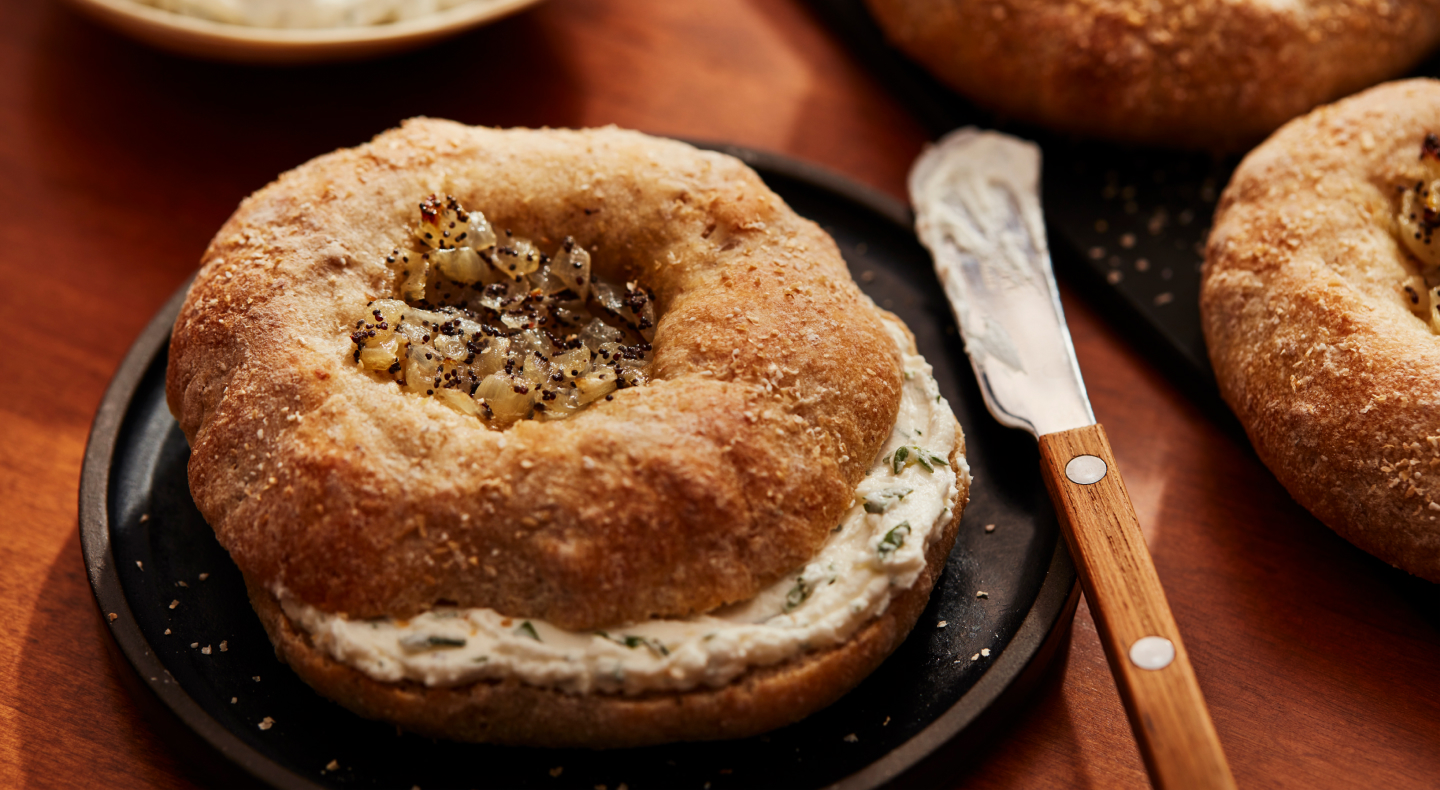 Prepared, spiced bagel with cream cheese inside, next to a spreading knife Prepared, spiced bagel with cream cheese inside, next to a spreading knife