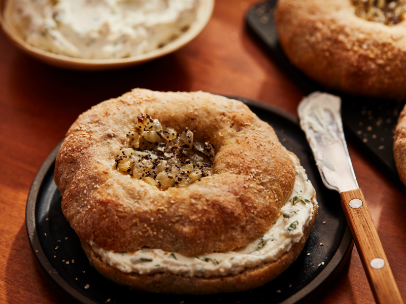 Prepared, spiced bagel with cream cheese inside, next to a spreading knife Prepared, spiced bagel with cream cheese inside, next to a spreading knife