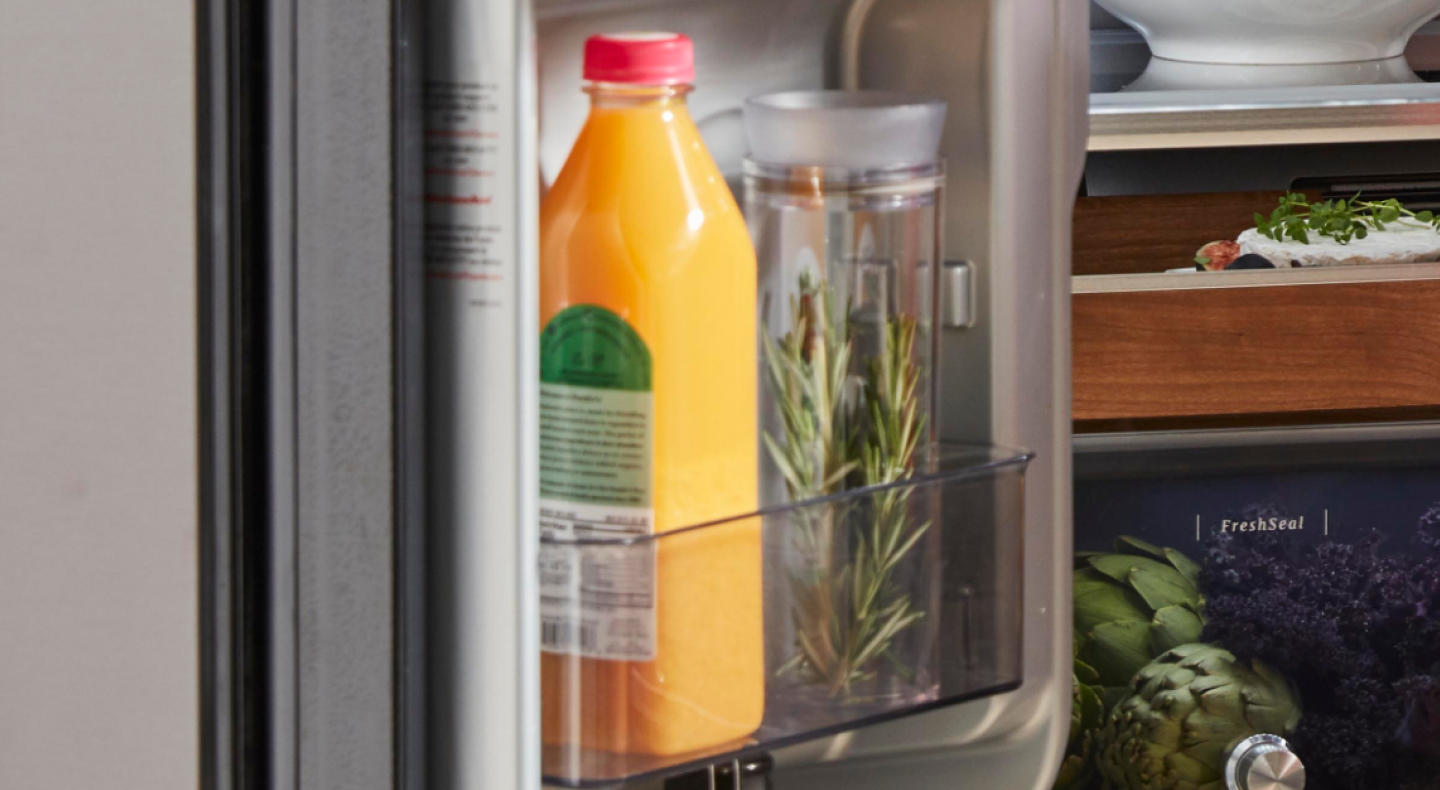 Jar of fresh rosemary in a refrigerator next to a bottle of orange juice Jar of fresh rosemary in a refrigerator next to a bottle of orange juice